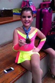 Mariana exibe uma medalha conquistada na patinação.